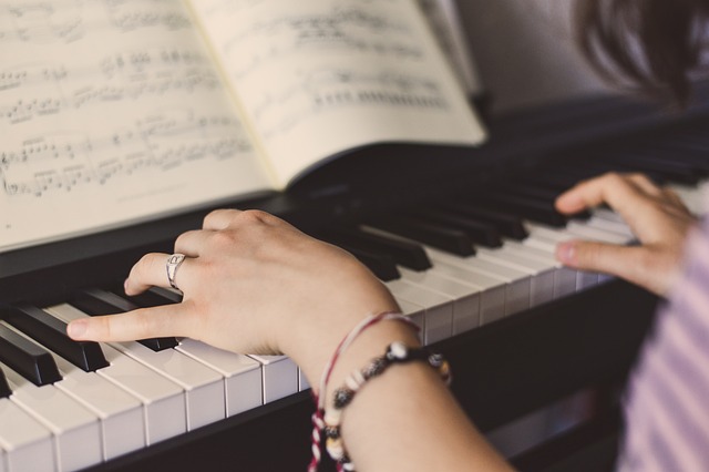 Närbild på en yngre persons händer som trycker ner pianots tangenter