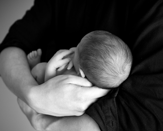 någon håller en bebis i famnen. Personen håller ena handen under huvudet.