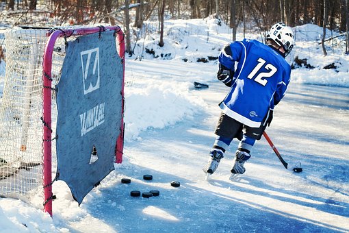 Ett barn som åker som spelar ishockey utomhus.