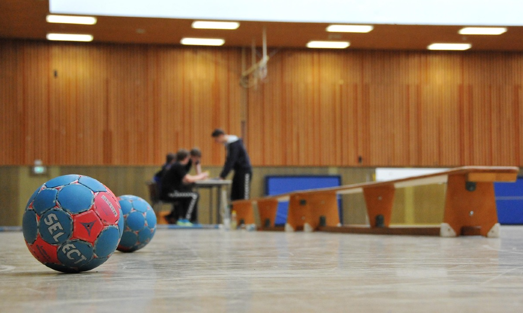 Sporthall med träpanel. Bollar och gymnastikbänkar framtagna.