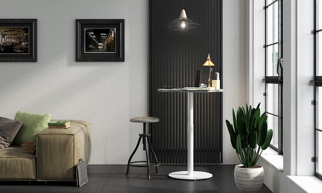 Ett ljus trum med soffa och ett ståbord. Emn pall och en stor krukväxt vid fönstret