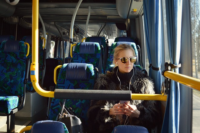 En passagerare som sitter i en buss. Den har blå inredning med gula detaljer.