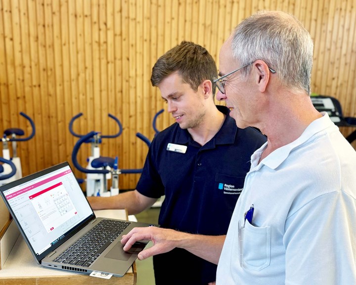 Fysioterapeuter visar nya digitala systemet på dator. Träningscyklar i bakgrunden