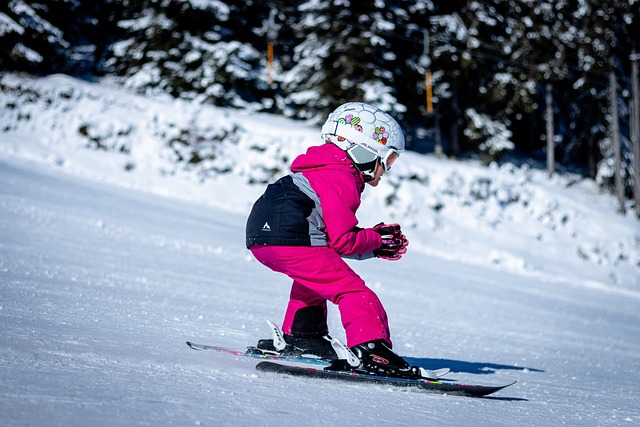 Barn åker slalom i skidbacke. Träd i bakgrunden.