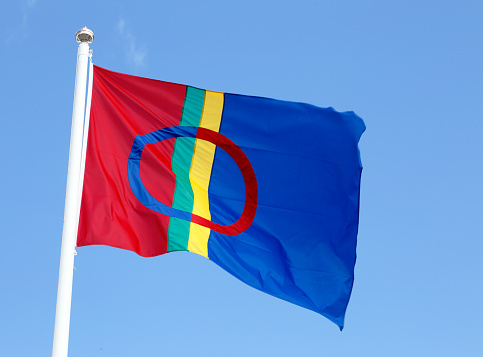 Samiska flaggan i röda, blå, gröna och gula fält. Och en ring i blått och rött.